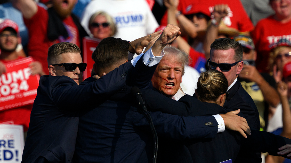 Then-candidate Trump is surrounded by Secret Service agents as streaks of blood are visible on his face following a failed assassination attempt in Butler, PA