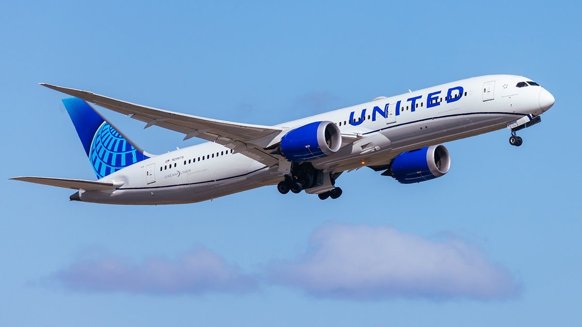 United Airlines Boeing 787 Dreamliner in flight with landing gear extended against a clear blue sky.