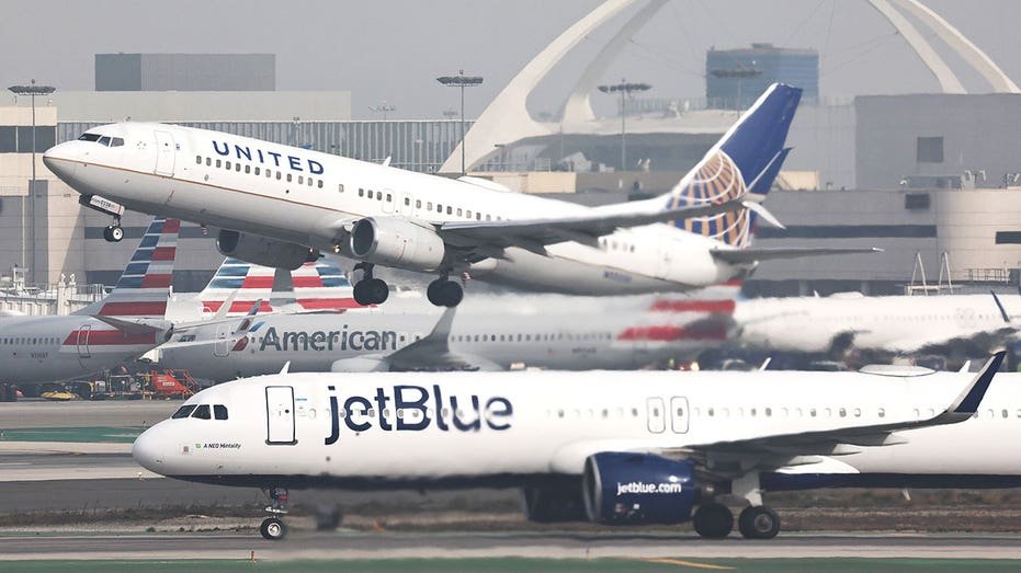 LOS ANGELES, CALIFORNIA - JANUARY 03: A JetBlue plane taxis after landing as a United plane takes off at Los Angeles International Airport (LAX) on January 03, 2025 in Los Angeles, California. JetBlue has been fined $2 million by the Department of Transportation for ‘operating multiple chronically delayed flights’ which marks the first time an airline has received such a penalty. (Photo by Mario Tama/Getty Images)