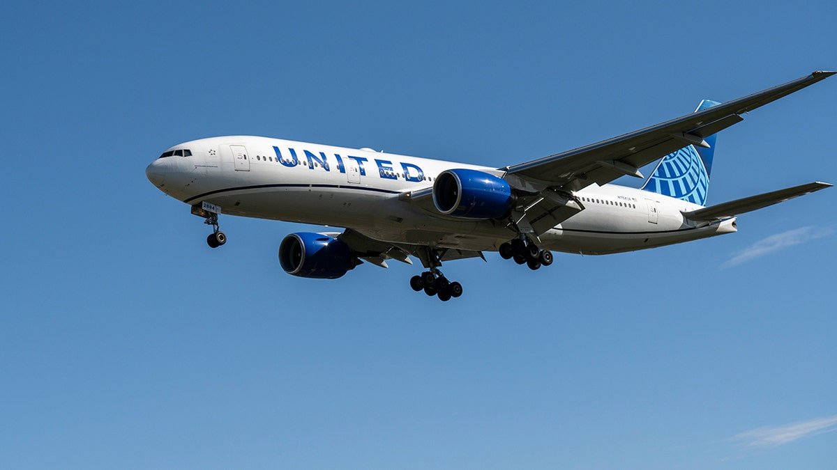 United Airlines plane flying in the blue sky.