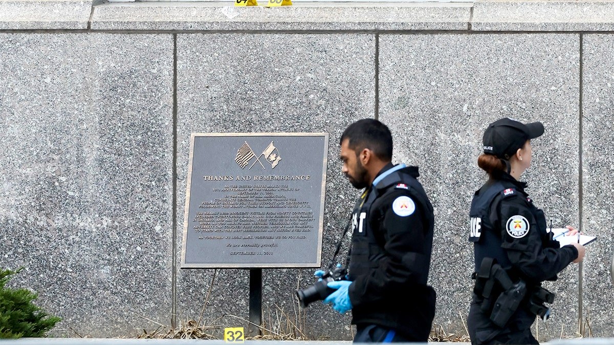 Police officers gather outside a secured diplomatic building in downtown Toronto following reports of gunfire.