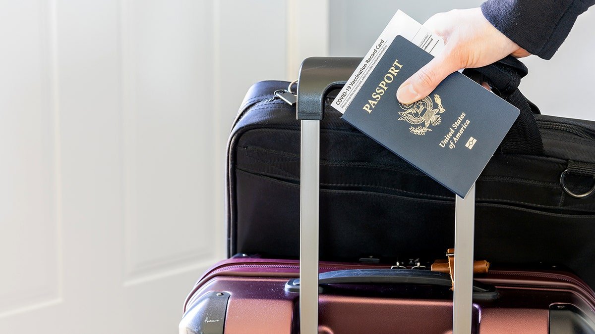 Close up of a woman's hand carrying a US passport and luggage.