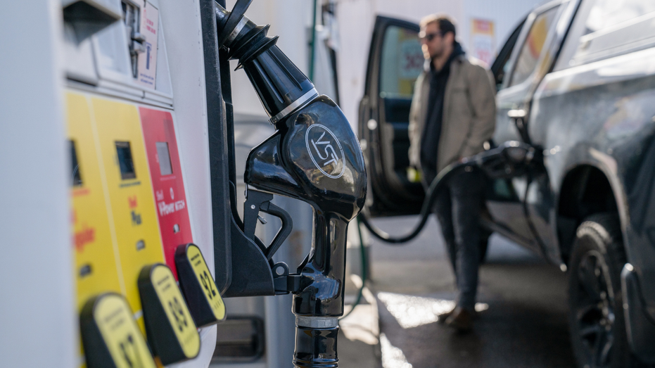 A man is seen pumping gas into his truck at a fuel station.