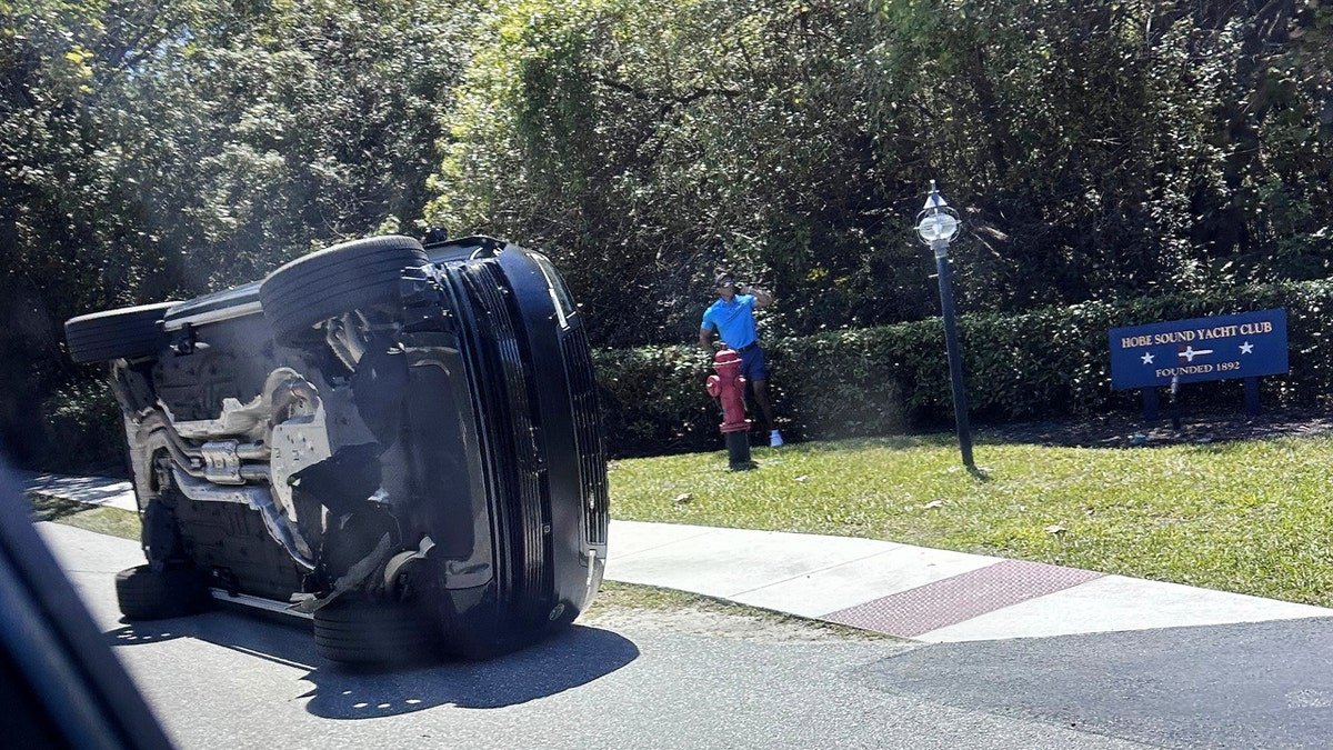 Golfer Tiger Woods stands by his overturned vehicle in Jupiter Island Florida