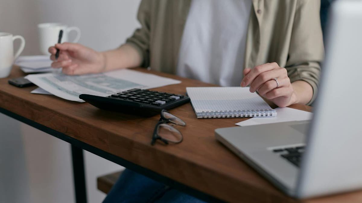 A woman preparing her taxes at a desk with documents and a calculator