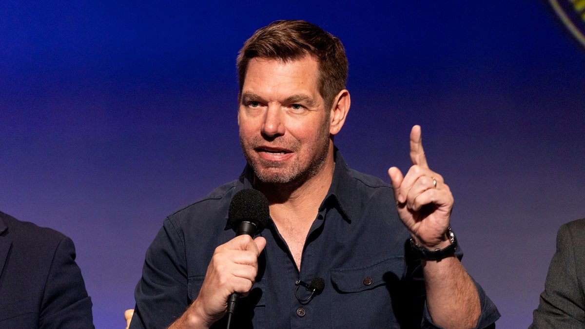 Rep. Eric Swalwell speaking and gesturing with finger raised at a microphone