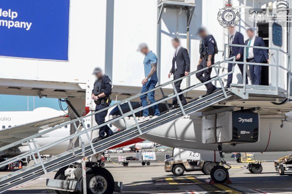 Ben Roberts-Smith is escorted off his flight by AFP officers upon arrival at Sydney Airport on Tuesday.