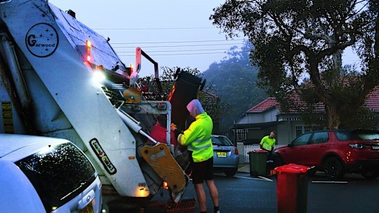 Men load rubbish into a truck that collects residential waste along Macauley street in Leichhardt.