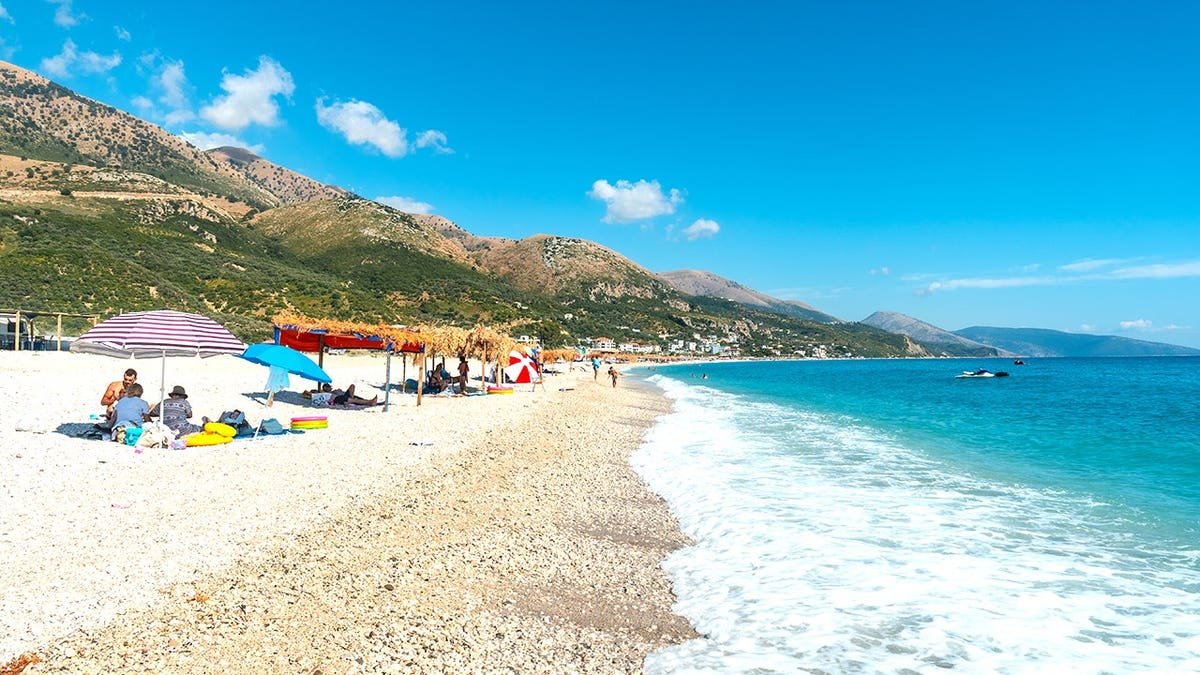Beachgoers under umbrella on Albanian beach near Adriatic Sea