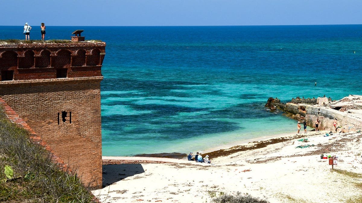 View of tourists looking out of Fort Jefferson, beachgoers below