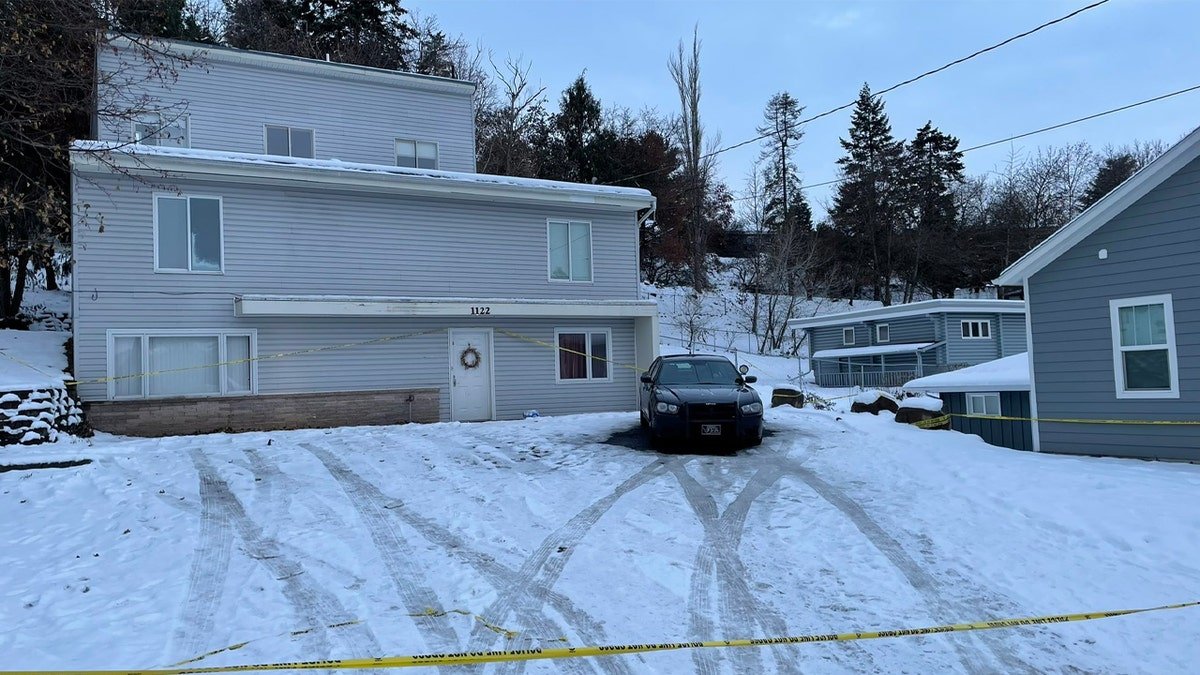 A watchman standing outside a house at 1122 King Road with snow and police tape