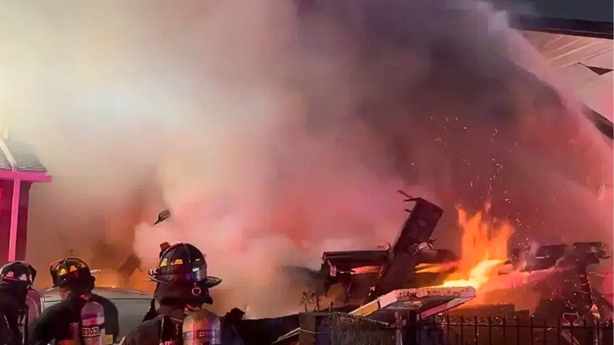 Firefighters spray water on a large home fire