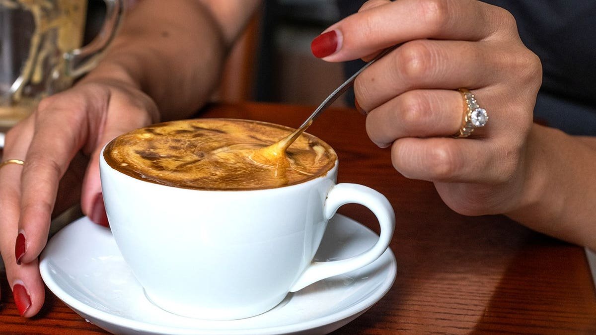 Woman stirring Vietnamese egg coffee in cafe