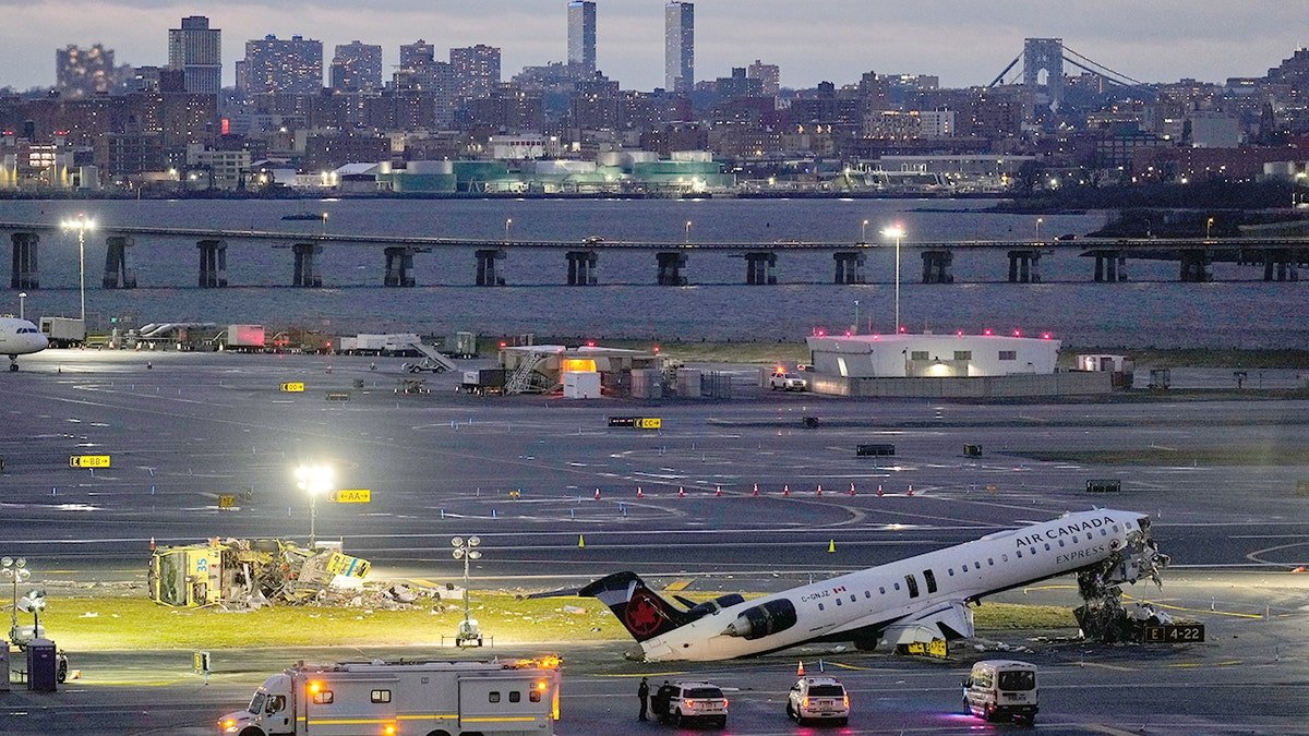 An Air Canada jet with severed cockpit next to damaged Port Authority fire truck on LaGuardia Airport runway