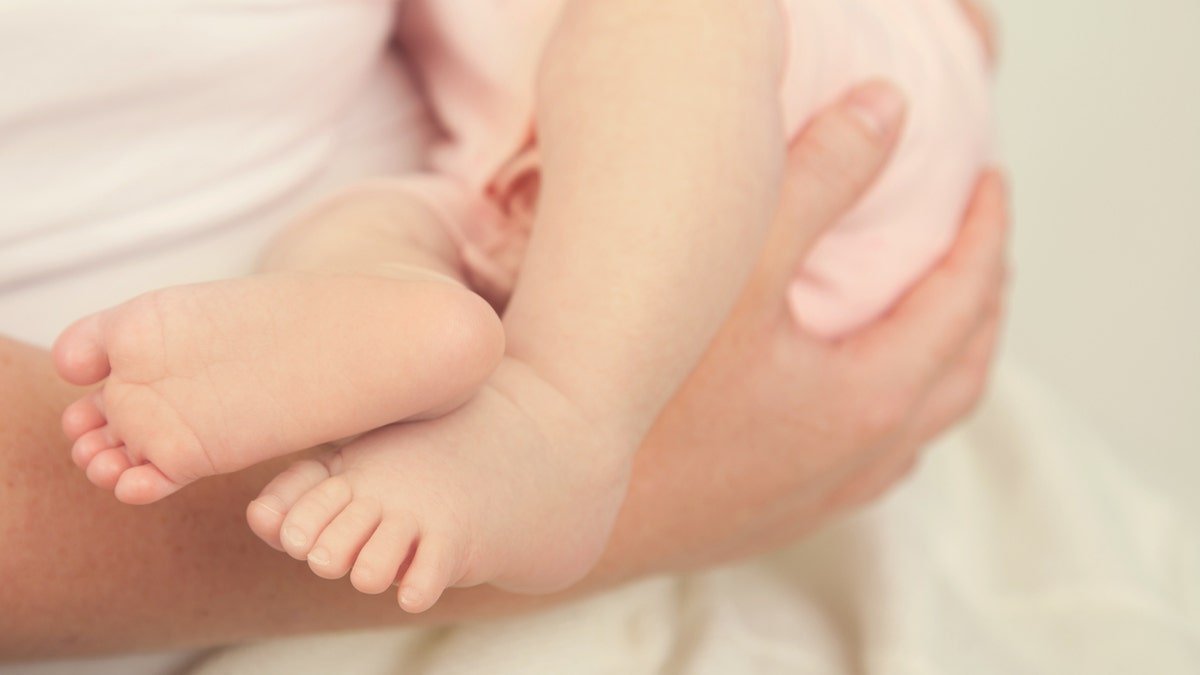 Baby Feet of baby girl being held by mother