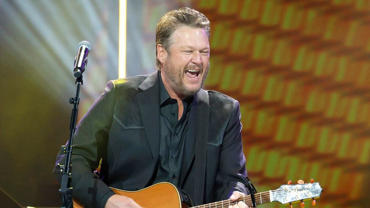 Blake Shelton singing and playing guitar on stage at The Grand Ole Opry