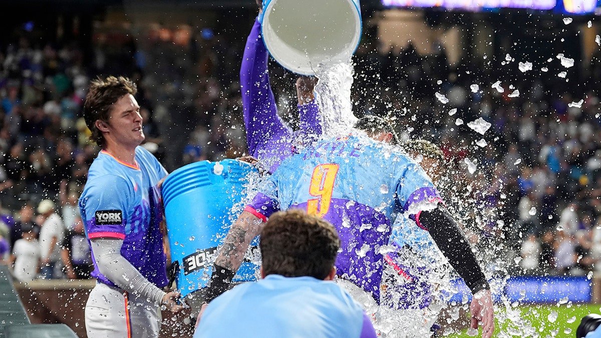 Brenton Doyle being doused by Mickey Moniak and Orlando Arcia after hitting a walkoff home run
