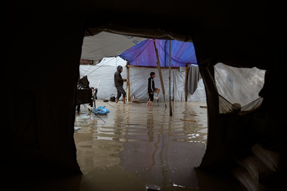 Displaced Palestinians walk through a rain-soaked tent camp following heavy rainfall at the end of March.