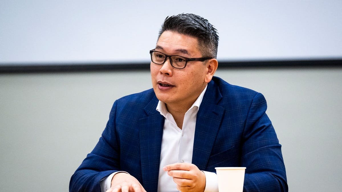 Derek Tran wearing glasses and suit speaking