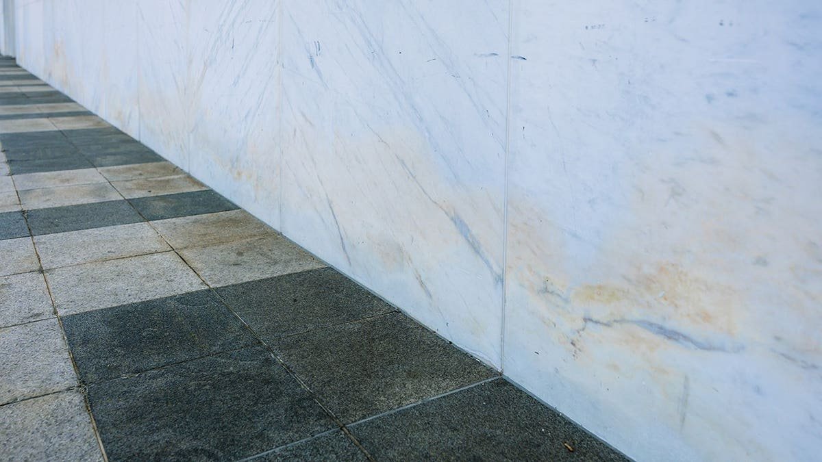 Discolored marble siding with visible staining and corrosion on stone panels