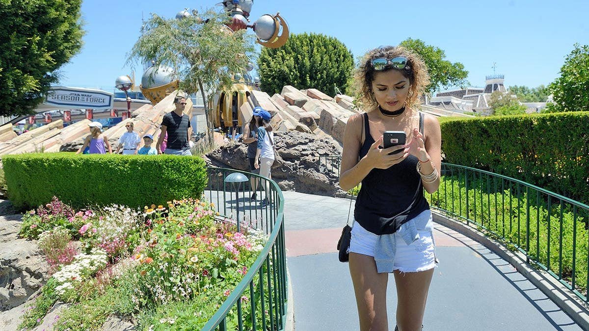 Michelle Mendez walking out of Tomorrowland playing Pokemon Go at Disneyland