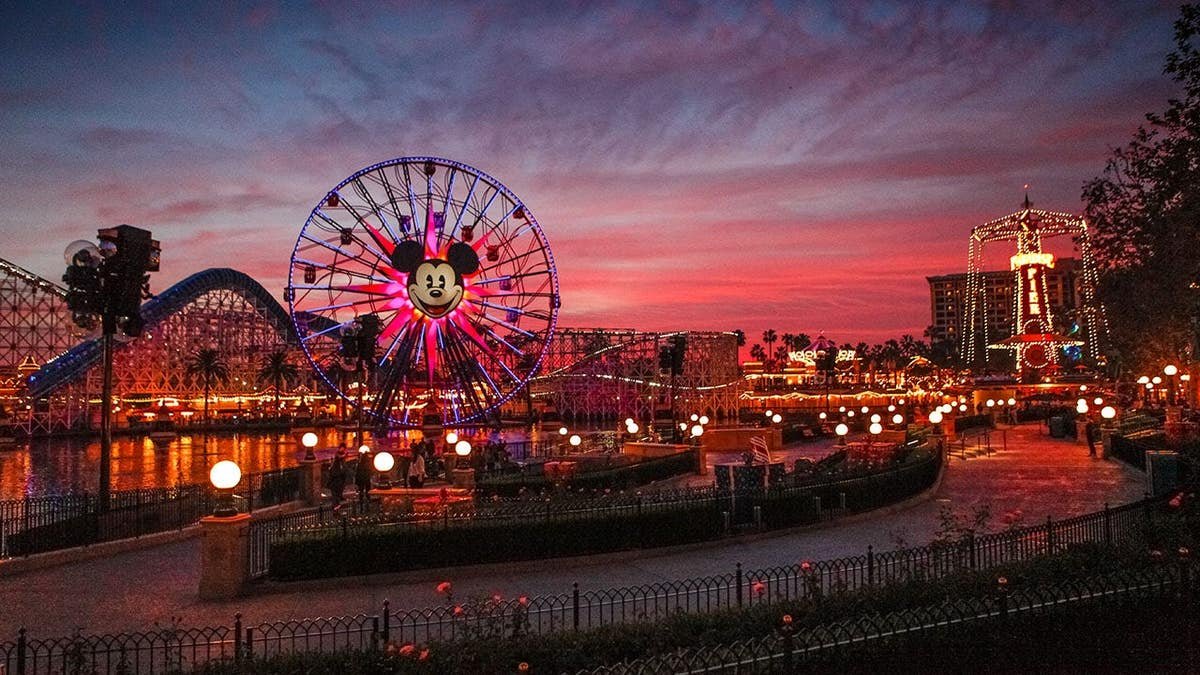 Tourists walking around Disney's California Adventure park at dusk