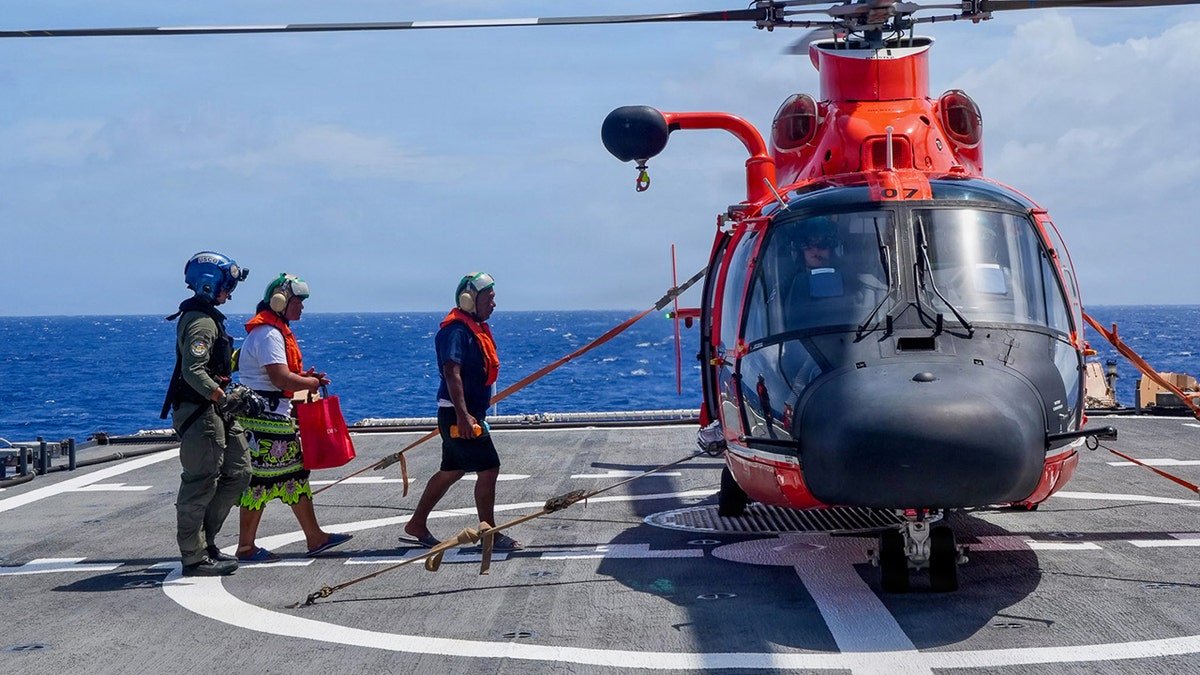 Family walking towards the helicopter after a U.S. Coast Guard rescue.