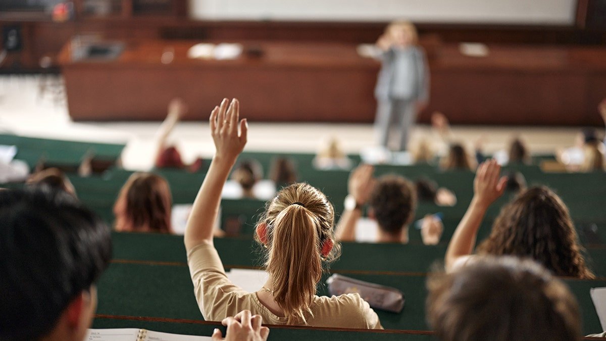Woman raising her hand in a college classroom amphitheater