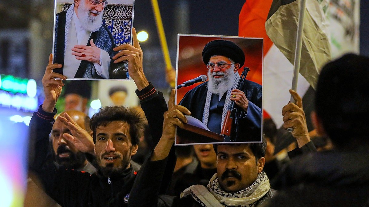 Iraqi Shiite men holding pictures of Ayatollah Ali Khamenei during a gathering in Najaf