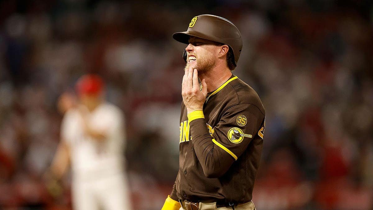 San Diego Padres' Jake Cronenworth reacting after being hit by a pitch during a baseball game.