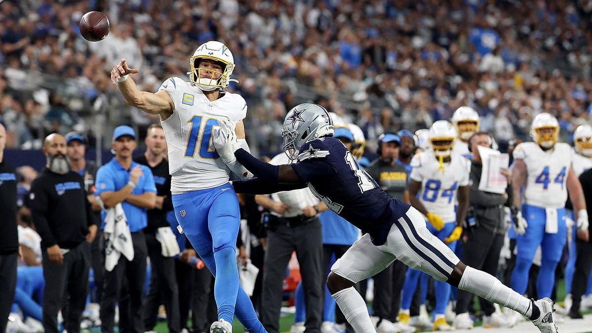 Justin Herbert of the Los Angeles Chargers is pursued by Markquese Bell of the Dallas Cowboys at AT&T Stadium
