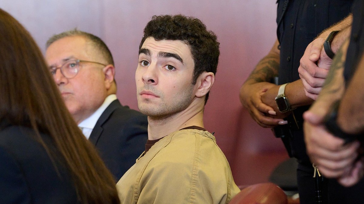 Luigi Mangione seated in court as judge drops terrorism charges.