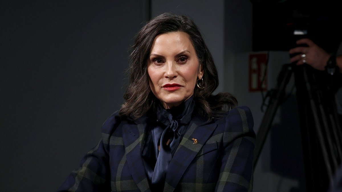 Michigan Governor Gretchen Whitmer listening to Rep. Alexandria Ocasio-Cortez speaking at a townhall panel