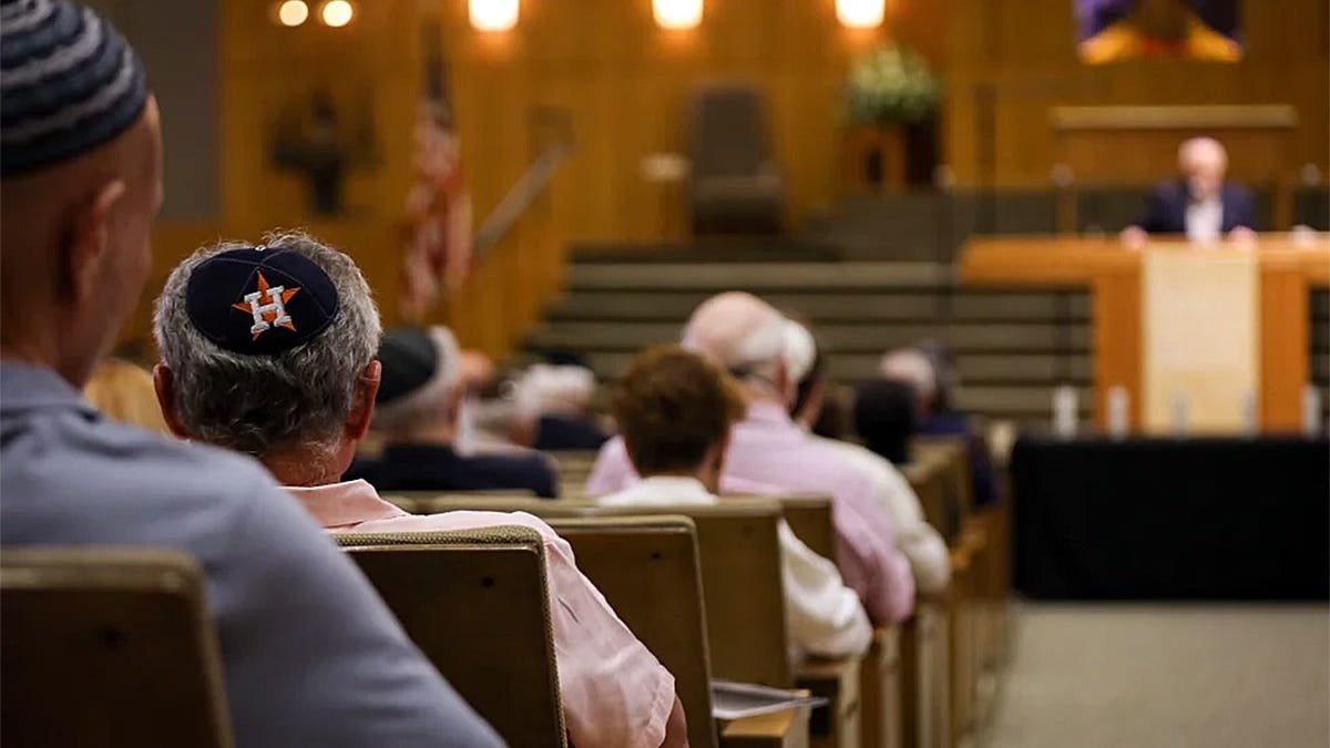 Interior of Congregation Beth Israel in Houston during a Holocaust Remembrance Day ceremony with attendees seated in rows.
