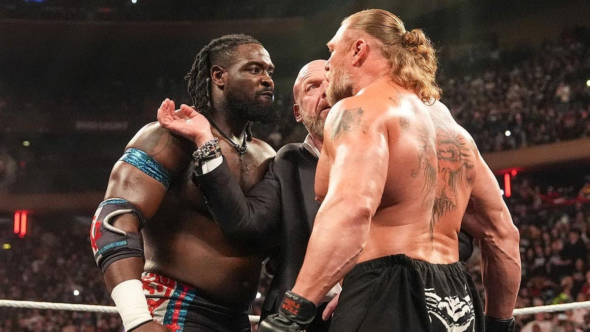 Oba Femi and Brock Lesnar face off in the ring with Triple H during Monday Night RAW at Madison Square Garden