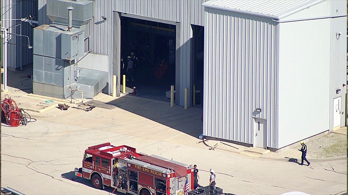 A close-up aerial view of an open garage-style door on a corrugated metal building with a fire truck parked in the foreground.