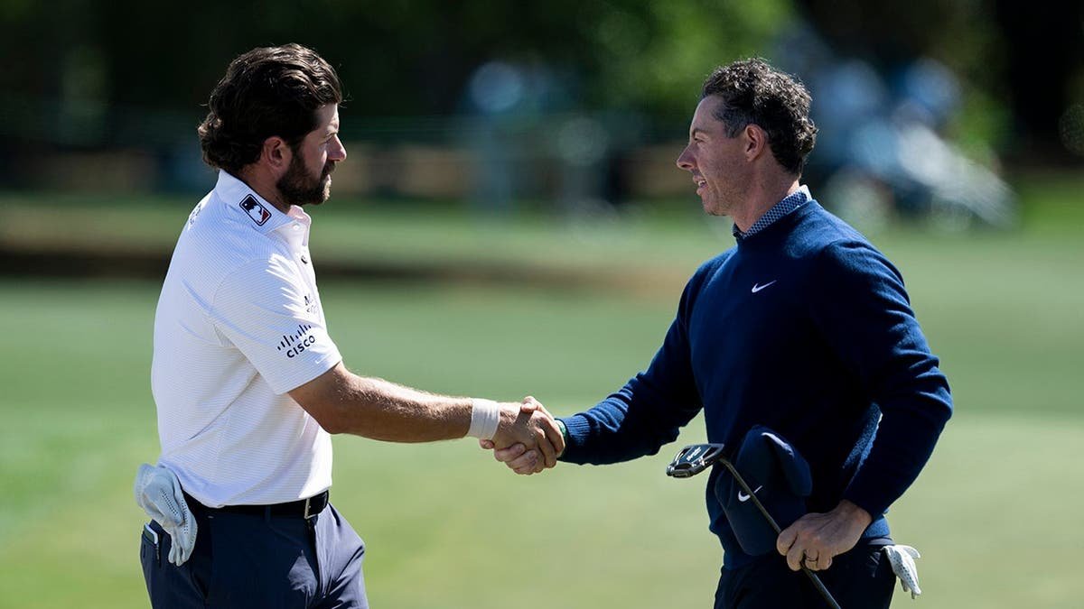 Rory McIlroy and Cameron Young shaking hands on the No. 18 green at Augusta National Golf Club