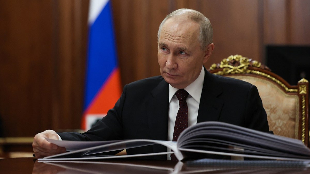 Russia's President Vladimir Putin sits at a table.