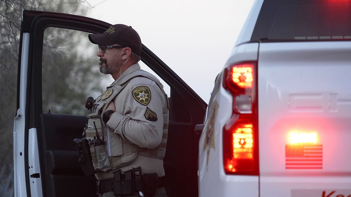 A Pima County Sheriff's Department member standing by a truck looking at Nancy Guthrie's house in Tucson