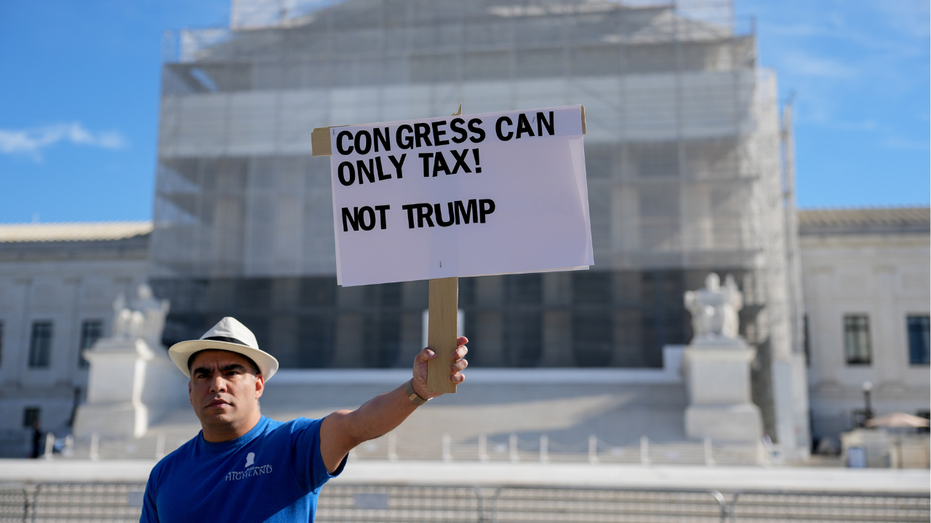 A demonstrator is seen outside the U.S. Supreme Court during oral arguments on President Donald Trump's trade policy.