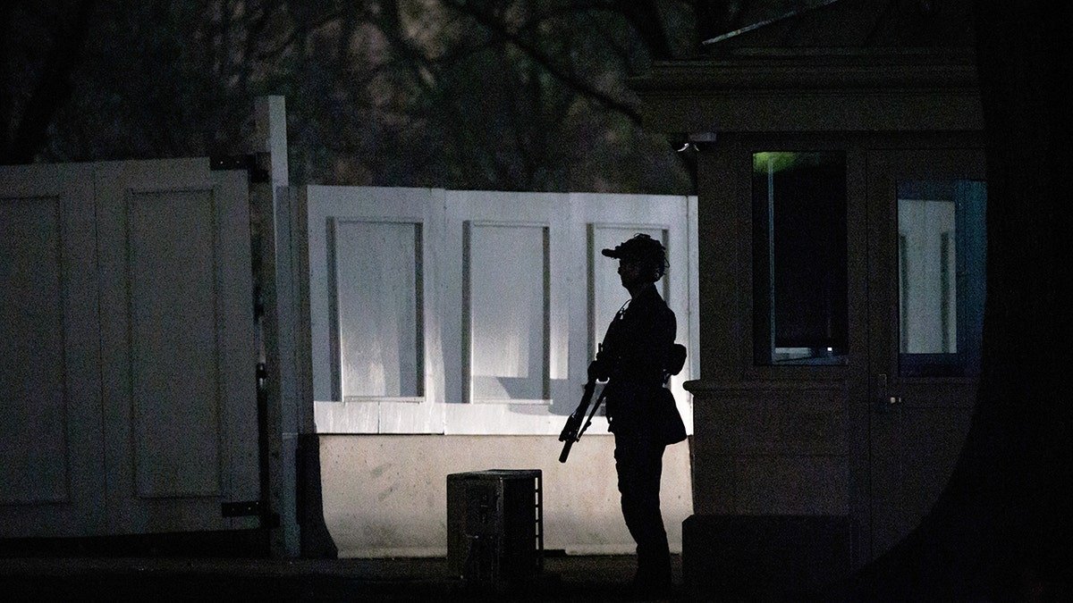 A US Secret Service agent in tactical gear standing on the South Lawn of the White House