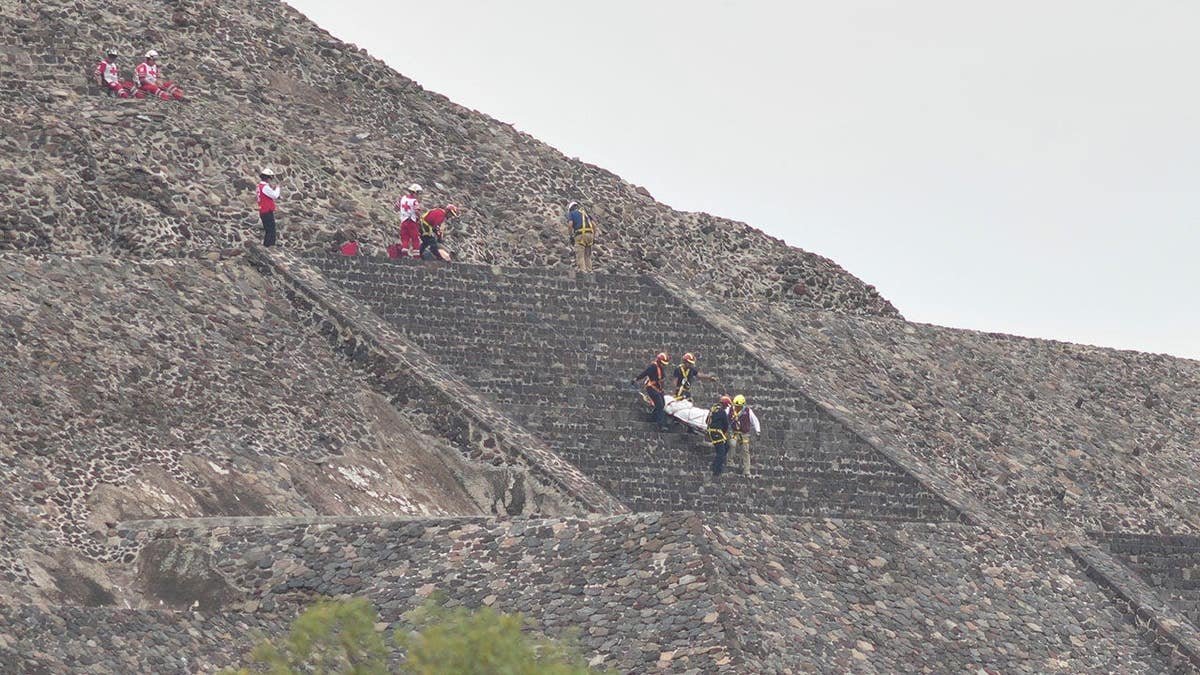 Forensic experts carrying a victim's body down a pyramid in Teotihuacan Mexico