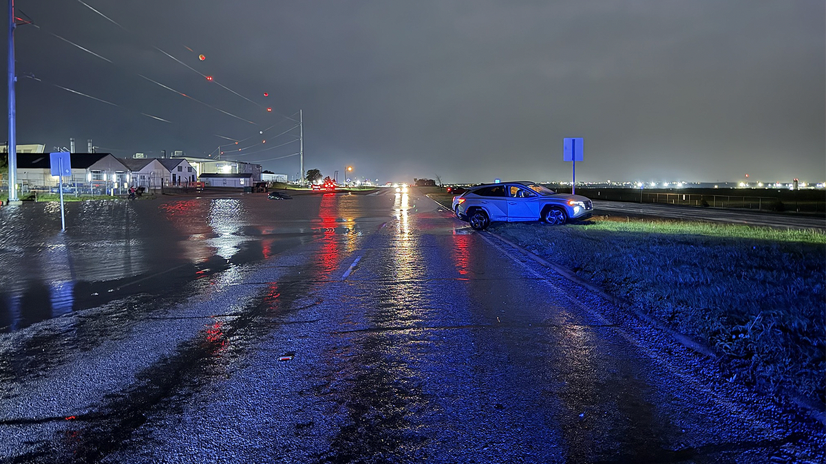 Flooded roadway at night with emergency lights during storm response in Texas
