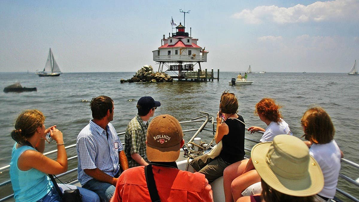 Visitors aboard small boat get ready to photograph Thomas point shoal lighthouse.