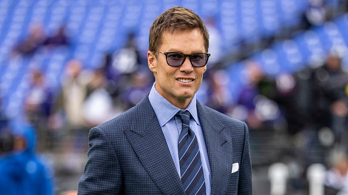 Former NFL quarterback Tom Brady reacting before a football game at M&T Bank Stadium.