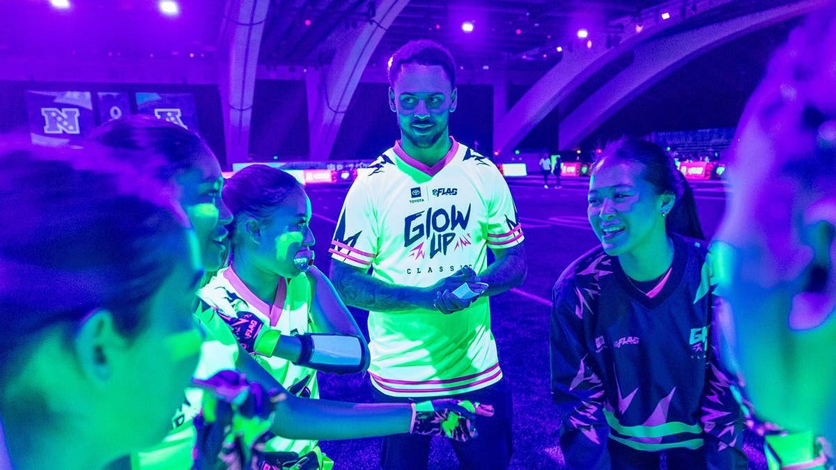 Youth players participating in glow-in-the-dark flag football at the Super Bowl Experience in San Francisco
