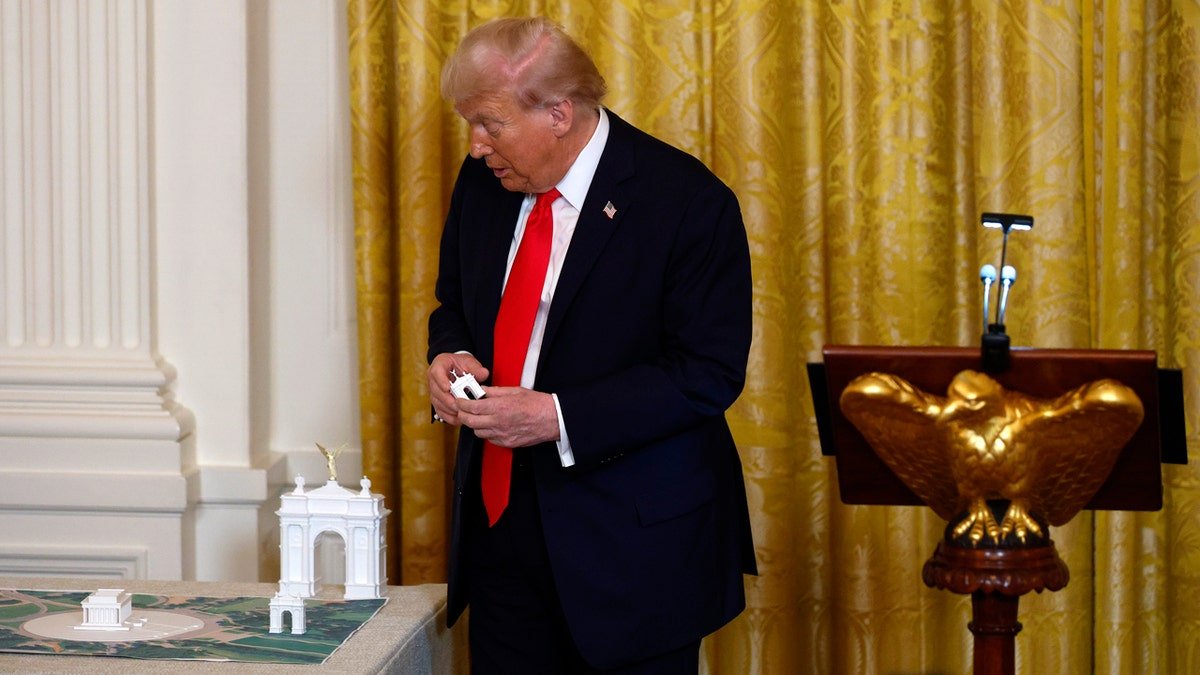 U.S. President Donald Trump holding a model of an arch in the East Room of the White House