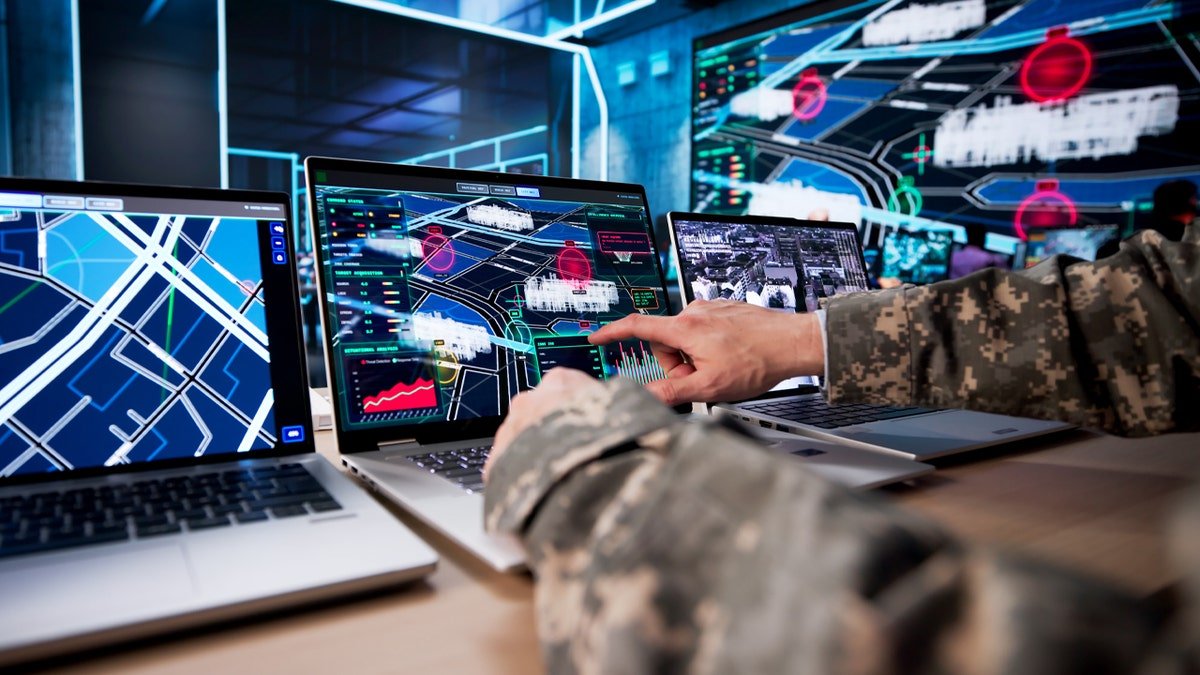 US servicemen standing in front of multiple computer screens in a control room