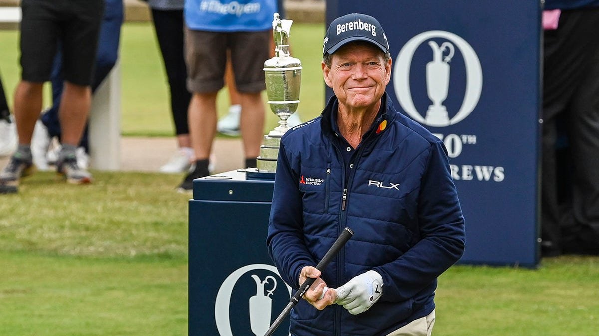 Tom Watson smiling walking past the Claret Jug on the first tee at St Andrews