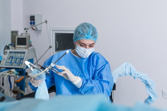 A nurse prepares a medical instrument for performing a hysteroscopy operation.